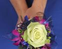 This fun prom bouquet features a single green rose with accents of fuschia flowers, purple ribbon, wire and feathers.