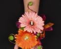 This pink and orange prom corsage features colorful daisies with hints of wire and crystal accents.